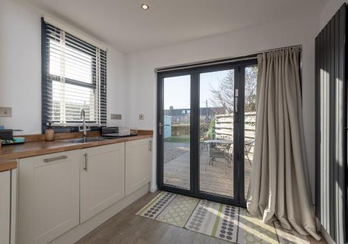 a kitchen with white cabinets and a sliding glass door at Sunset Retreat in Gullane