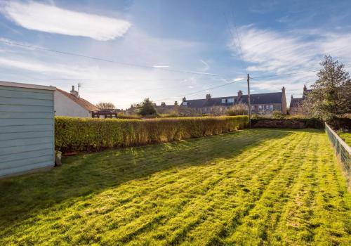 a grassy yard with a hedge and a house at Sunset Retreat in Gullane