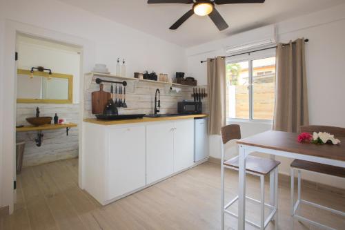 a kitchen with white cabinets and a table and a ceiling fan at Treetops Hotel in Caye Caulker