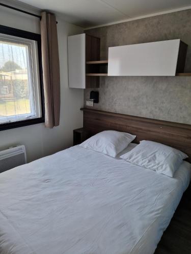 une chambre avec un lit blanc et une fenêtre dans l'établissement Mobilehome familial, à Gastes