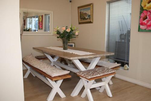 a dining room table with benches and a vase of flowers at Tygerviews on Uys in Tygerberg Hills