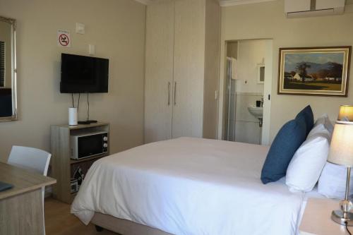 a bedroom with a white bed and a flat screen tv at Tygerviews on Uys in Tygerberg Hills