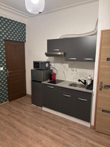une cuisine avec un évier et un micro-ondes dans l'établissement STUDIO TOUT EQUIPE 50 M DE LA GARE D'ENGHIEN LES BAINs 15 MN DE PARIS CENTRE, à Enghien-les-Bains