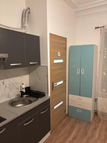La cuisine est équipée d'un évier et d'un réfrigérateur bleu. dans l'établissement STUDIO TOUT EQUIPE 50 M DE LA GARE D'ENGHIEN LES BAINs 15 MN DE PARIS CENTRE, à Enghien-les-Bains