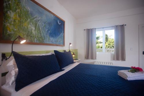 a bedroom with a blue bed with a large painting on the wall at Treetops Hotel in Caye Caulker