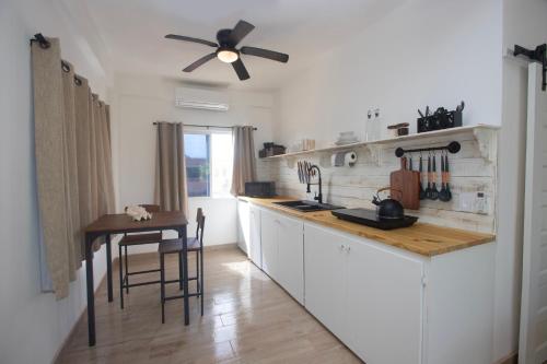 a kitchen with white cabinets and a ceiling fan at Treetops Hotel in Caye Caulker