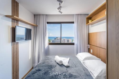 a bedroom with a bed with a view of the ocean at Apartamentos em Prédio c/ Piscina na Ondina - SSA - HOA in Salvador