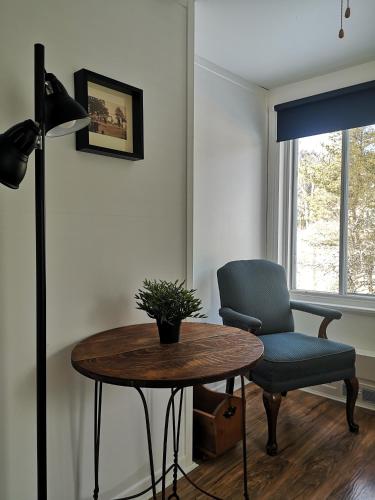 a room with a table and a chair and a lamp at Auberge de la rive de Charlevoix - Auberge de jeunesse familiale pour voyageurs de tous âges in Saint-Joseph-de-la-Rive