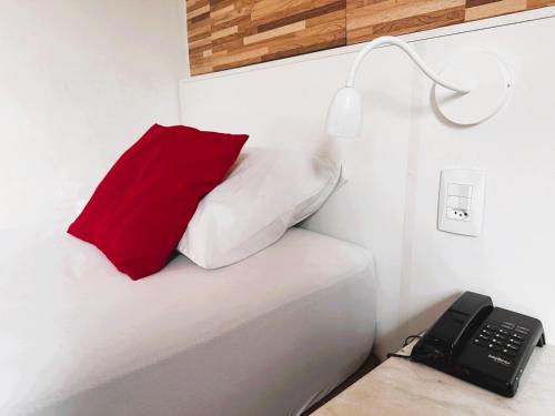 a bed with a red pillow and a telephone at Memorial Hotel in São Paulo