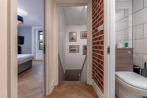 a bathroom with a toilet and a brick wall at City View Flat, Quiet Bedroom, Work Ready Desk in Bristol