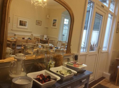 een eetkamer met een spiegel en wat eten op een tafel bij The Maples in Hythe