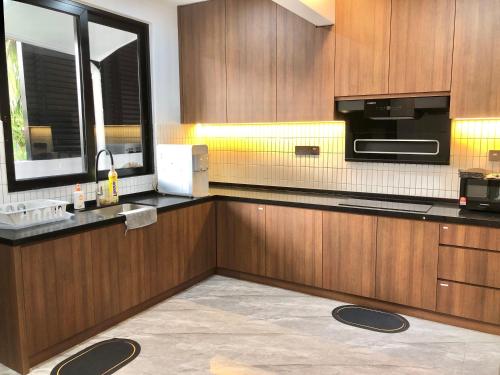a kitchen with wooden cabinets and a sink and a microwave at BigLanded House NR Penang Hill & Kek Lok Si Temple in Ayer Itam
