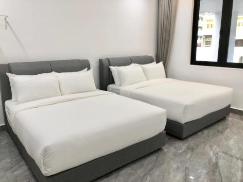 two beds in a room with white sheets and pillows at BigLanded House NR Penang Hill & Kek Lok Si Temple in Ayer Itam