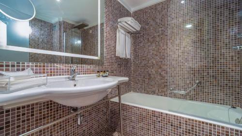 a bathroom with a sink and a tub and a mirror at St George Lycabettus Lifestyle Hotel in Athens