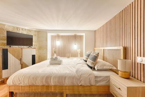 une chambre avec un grand lit blanc et une télévision dans l'établissement Appartement Duplex Atypique au coeur du Sentier, à Paris