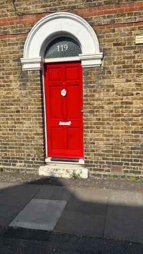 a red door on the side of a brick building at The Red Door House in London