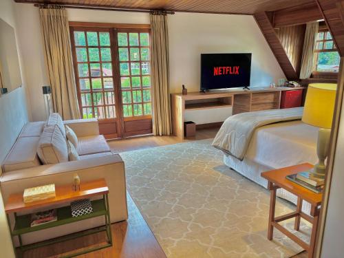 a bedroom with a king sized bed and a television at Casa Três Rios - Campos do Jordão in Campos do Jordão