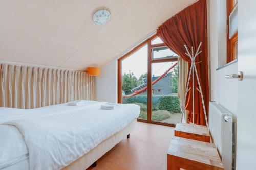 a bedroom with a bed and a large window at Dutchen Vakantiepark Buiten Bergen in Schoorl
