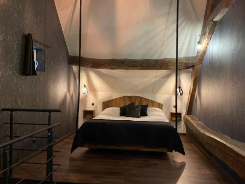 - une chambre dotée d'un lit suspendu avec des draps et des oreillers noirs dans l'établissement Domaine de Vandenesse Et Spa, à Vandenesse-en-Auxois