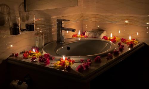 a bathroom with a sink with candles and flowers at Abuharee Grand in Hithadhoo