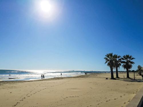 a beach with palm trees and the ocean on a sunny day at Holiday Home Jorge Comin by Interhome in Benicàssim