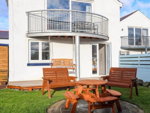three benches and a table in front of a house at Seaside Sanctuary in Holyhead