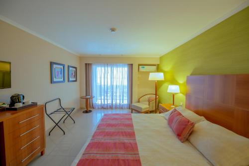 a hotel room with a large bed with a dresser and a bedroom at Condado Hotel Casino Paso de la Patria in Paso de la Patria