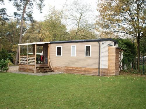 a small cabin with a deck in a yard at Holiday Home De Brenkberg-1 by Interhome in Schinveld