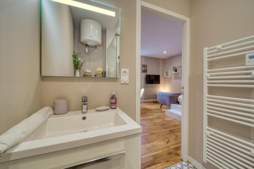 une salle de bain blanche avec un lavabo et un miroir dans l'établissement R'Apparts Studio Art Deco, à Grenoble