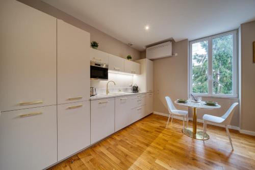 une cuisine avec des armoires blanches, une table et une fenêtre dans l'établissement R'Apparts Studio Art Deco, à Grenoble