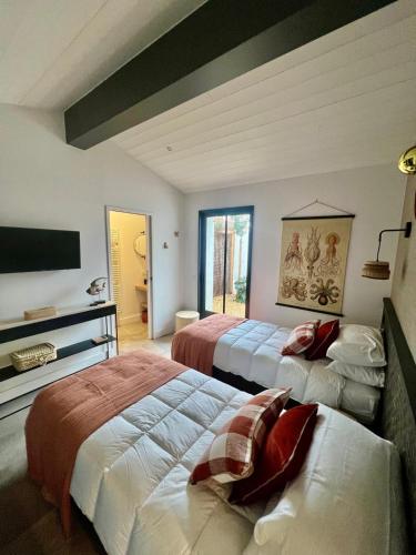 une chambre avec deux lits et une télévision à écran plat dans l'établissement Les Villas du Bois, au Bois-Plage-en-Ré