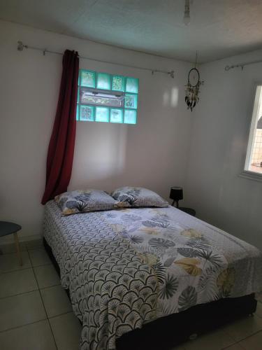 a bedroom with a bed and a window at Villa letchi in LʼEntre-Deux