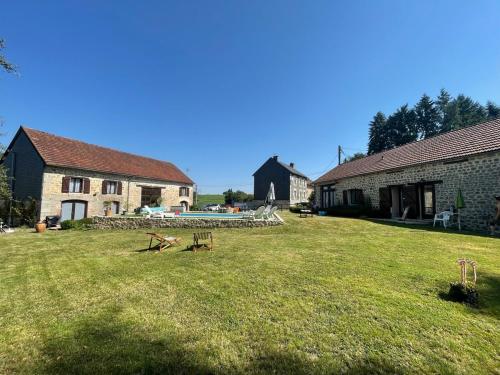 a yard with two buildings and a table in the grass at Domaine Pâquerettes et Pïssenlits in Le Pommier