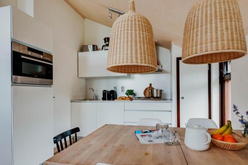 a kitchen with a wooden table and two hanging lights at Dutchen Vakantiepark Buiten Bergen in Schoorl