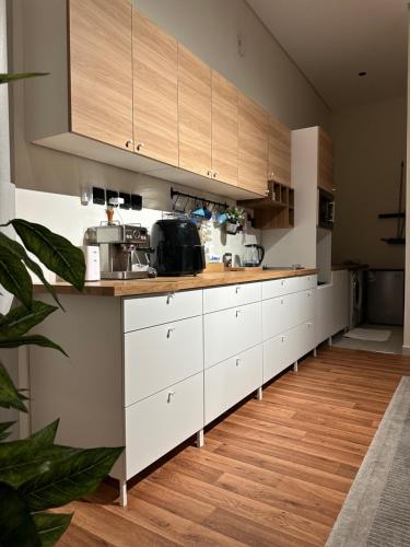 a kitchen with white cabinets and a wooden floor at شقة فاخرة بغرفة سينما وحديقة in Qabāʼ