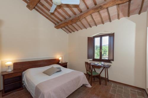 a bedroom with a bed and a desk and a window at Country House Le Case Coloniche in Deruta
