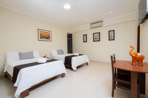 a bedroom with two beds and a table and a desk at Hotel San Marino Tarapoto in Tarapoto