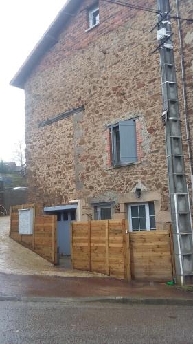 un bâtiment en briques avec une clôture en bois devant lui dans l'établissement Le petit nid aux bords de vienne, à Limoges