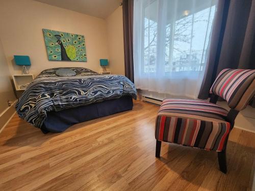 a bedroom with a bed and a window and a chair at Maison 3 chambres Inspiration in Amos