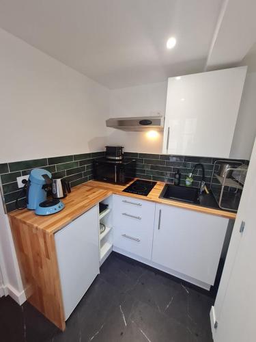 une cuisine avec des armoires blanches et des comptoirs en bois dans l'établissement Charmant studio rénové, à Caen