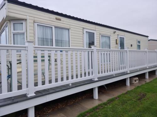 a mobile home with a white railing on a deck at 6 Berth Caravan The Grange Ingoldmells in Skegness