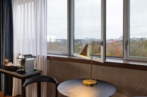 a room with a desk with a lamp and windows at Best Western Plus Hôtel Isidore in Saint-Jacques-de-la-Lande