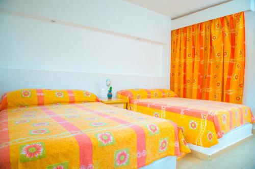 two beds in a bedroom with orange and pink sheets at Hotel Acapulco in Acapulco