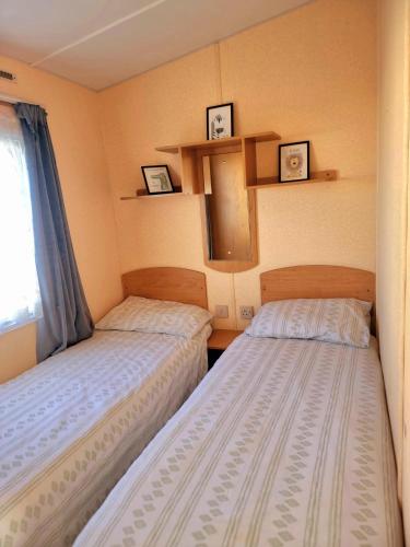 two beds in a small room with pictures on the wall at 6 Berth Caravan The Grange Ingoldmells in Skegness