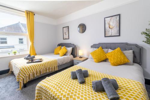 two beds in a room with yellow pillows at Open Mind Property - 2 BR, 4 Beds & 9 Guests in Portsmouth