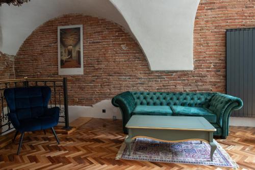 a living room with a green couch and a brick wall at MAGISTER seven in Sibiu