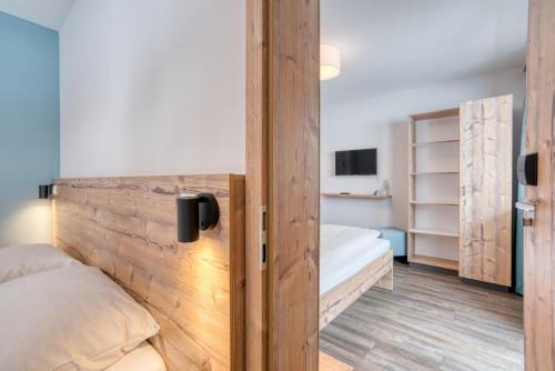 a bedroom with two beds and a wooden wall at COOEE alpin Hotel Bad Kleinkirchheim in Bad Kleinkirchheim