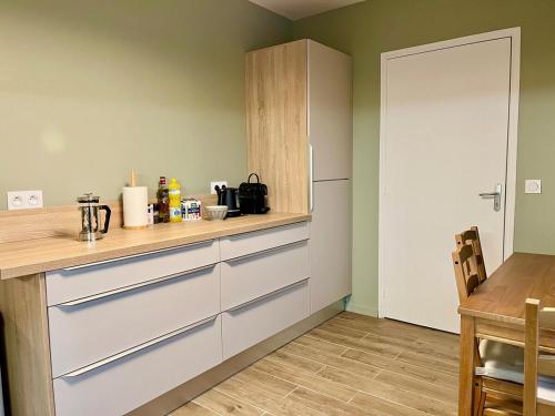 - une cuisine avec des placards blancs, une table et un réfrigérateur dans l'établissement La Maison des Vignes de Cernay, à Cernay-lès-Reims