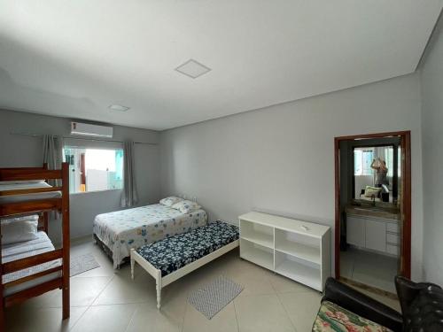 a bedroom with two beds and a dresser and a mirror at Casa Rosa Pestana - min da Praia - PRADO BAHIA in Prado
