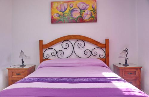 a bed in a bedroom with two nightstands and a painting at Chalet Vigía 114 in Conil de la Frontera